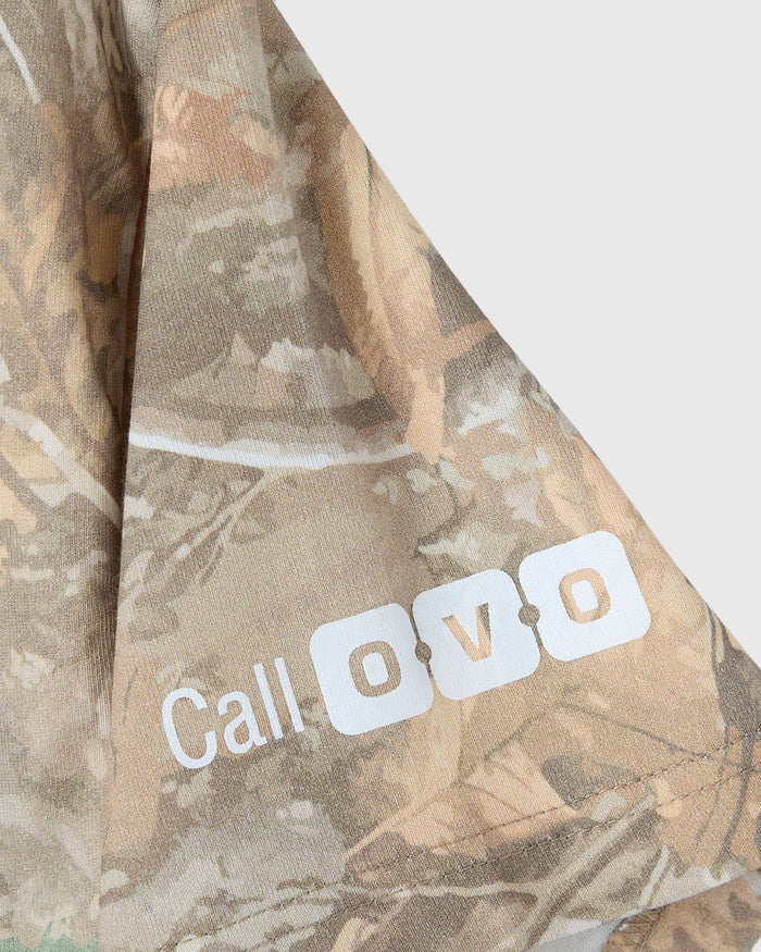 Tan camouflage t-shirt with cold shoulder cutout and "Call 0770" text printed on sleeve.