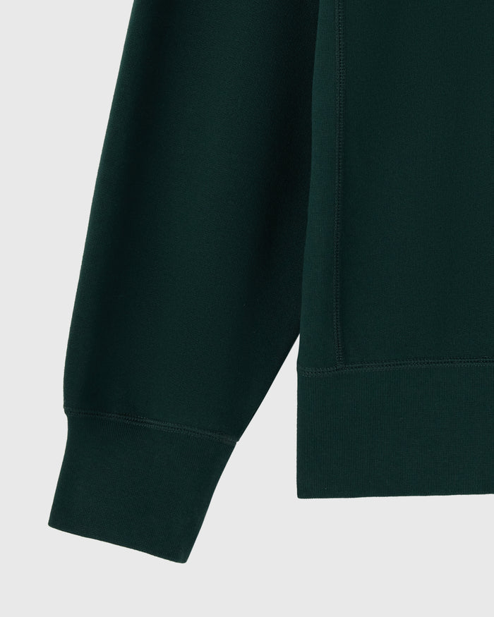 Midnight green crewneck sweatshirt with ribbed cuffs and hem detail shown from side angle.