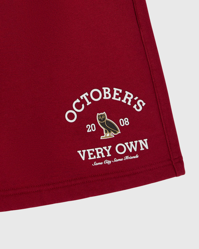 Deep red shorts with "October's Very Own" graphic and owl emblem printed on thigh.