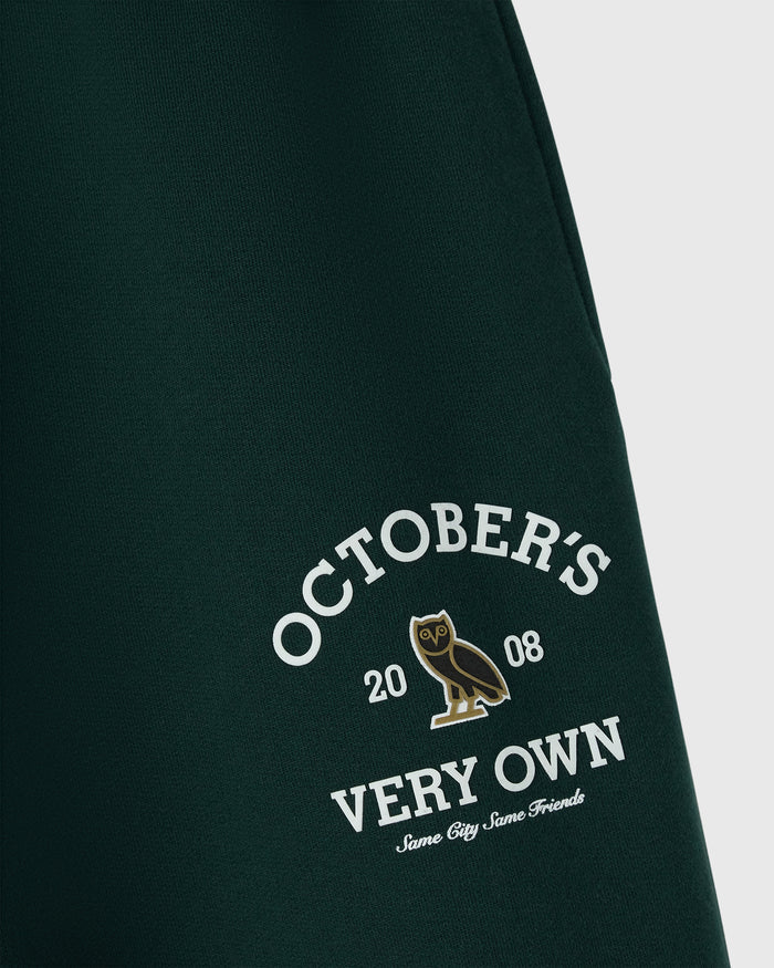 Midnight green sweatpant with white "October's Very Own" text and gold owl graphic on leg.
