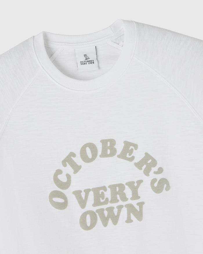 White raglan tee with "October's Very Own" text graphic in beige across the chest.