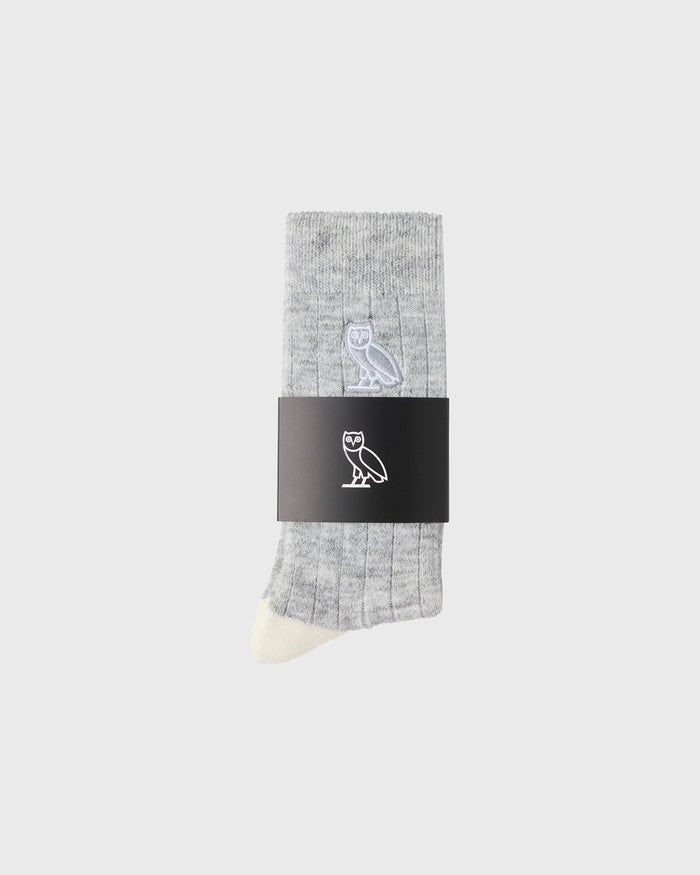 Gray crew sock with white owl logo and cream-colored toe, displayed with black brand label band.