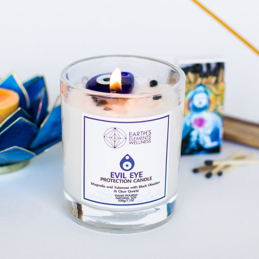 Candle in a glass jar with a label on a white surface, surrounded by decorative items.