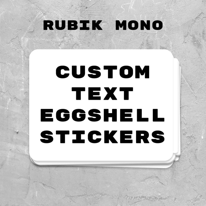 Stack of custom text eggshell stickers with 'Rubik Mono' branding on a gray textured background.