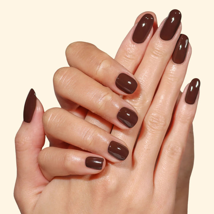 Two hands with neatly manicured nails painted in LONDONTOWN’s Double Fudge, a rich chocolate brown glossy shade, are held together against a plain light background.