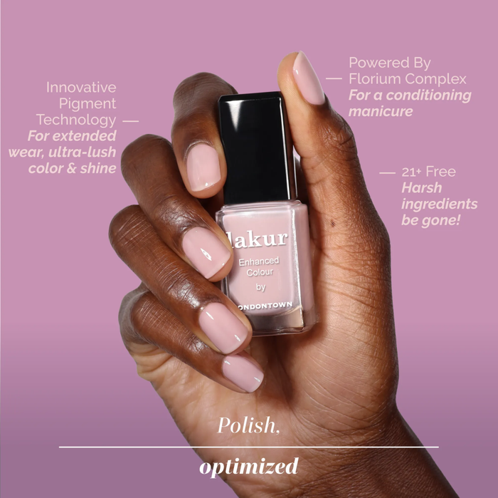 A hand with neatly manicured nails holds a bottle of LONDONTOWN Dream State nail polish, featuring innovative pigment technology, a soft glow finish, and a formula free from harsh ingredients.