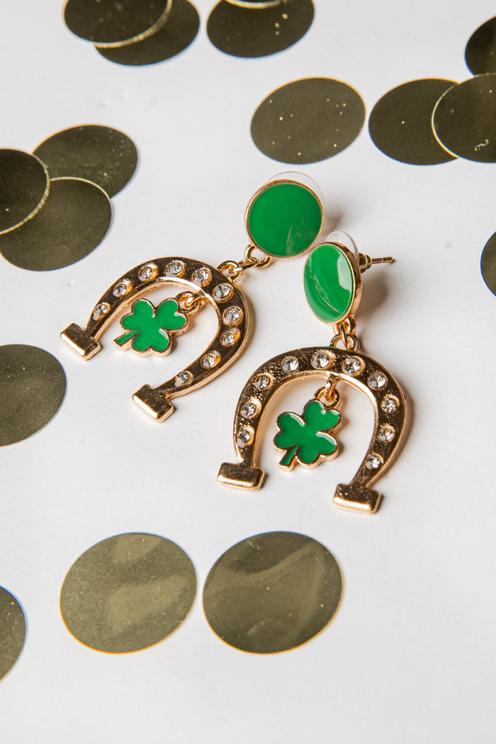 Gold earrings with green shamrock designs on a white background with gold coins.