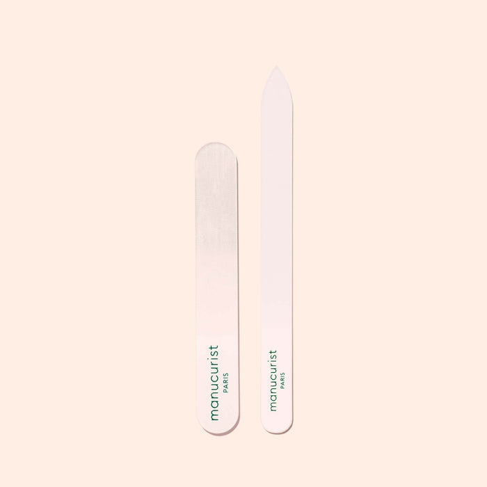Two Manucurist-us Glass Polishers are displayed on a light beige background—one rounded, one pointed. Both feature the brand's green logo and are ideal for smoothing the natural nail plate and adding shine.