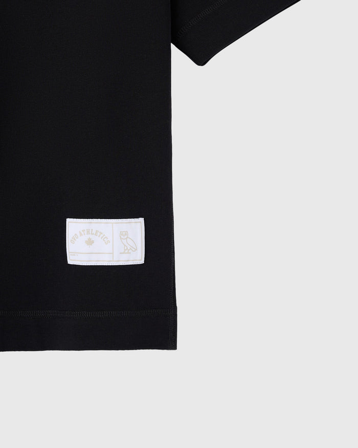 Black heavyweight t-shirt with white woven label featuring mascot owl graphic on left sleeve.