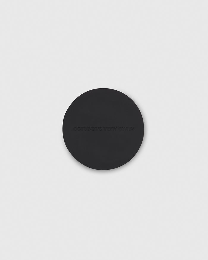 Black circular coaster with embossed text on surface.