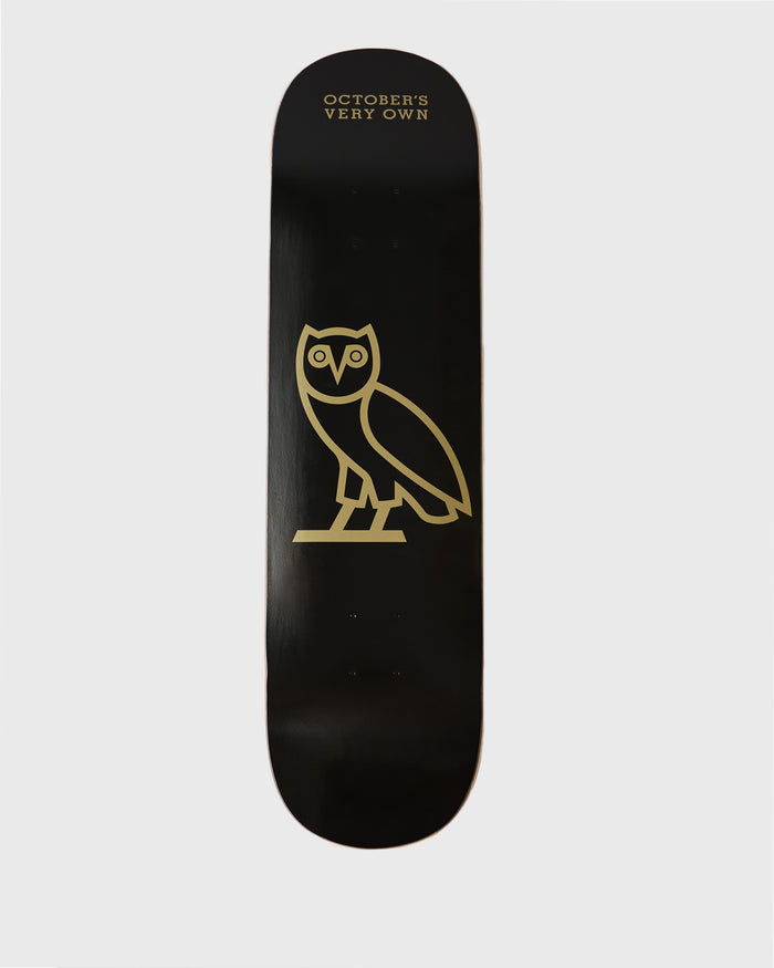 Black skateboard deck with gold owl graphic and "October's Very Own" text on top.