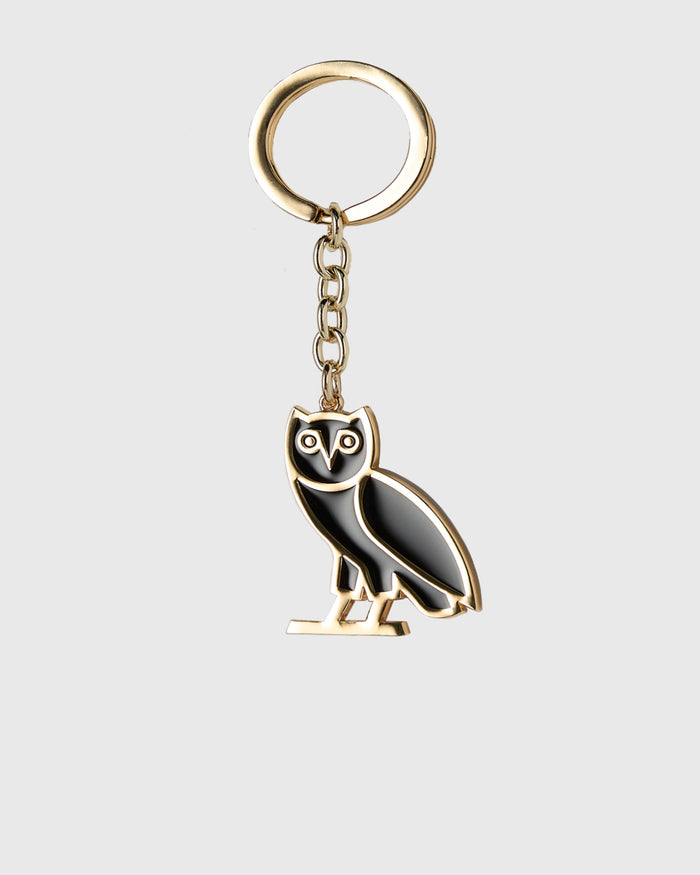 Gold-toned metal keychain with black enamel owl charm hanging from chain and split ring.