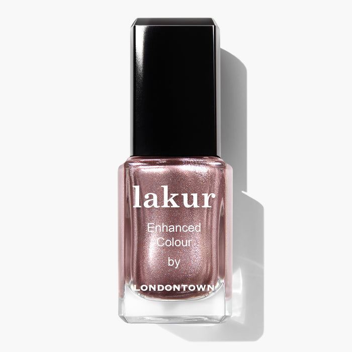 A bottle of LONDONTOWN's Kissed by Rose Gold Lakur Enhanced Colour, featuring a cruelty-free and vegan formula in a stunning metallic rose gold shade with a black cap, beautifully photographed against a white background.