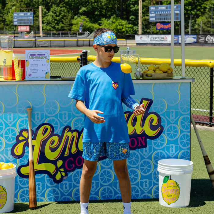 Youth model wearing blue youth graphic tee with "Lemonade" design