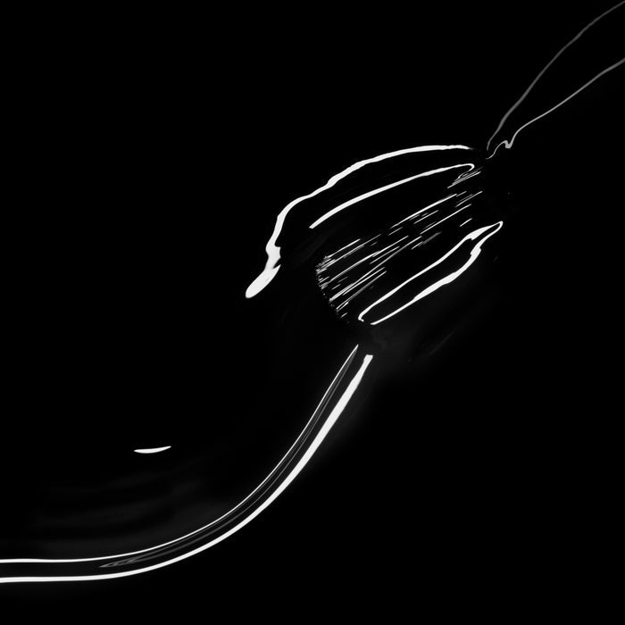 A metal fork gleams with Licorice by Manucurist, its chic black nail polish-like reflections shining boldly against a pitch-black background.