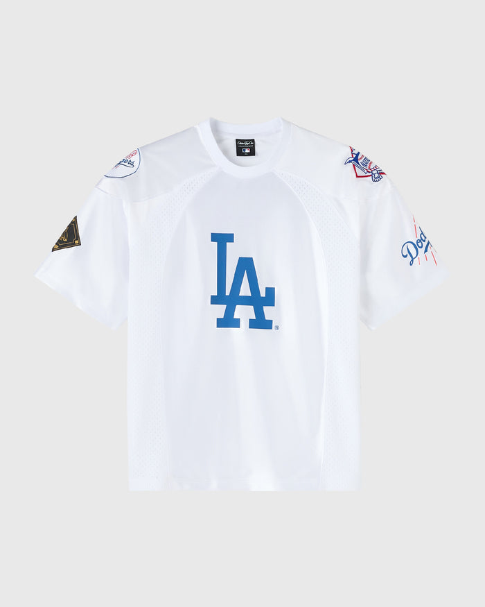 A white Los Angeles Dodgers short-sleeve athletic jersey with a large blue 'LA' logo on the chest, displayed against a light gray background.