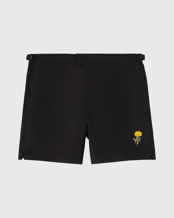 Black swim shorts with side vents and yellow marigold flower embroidery on the right thigh.