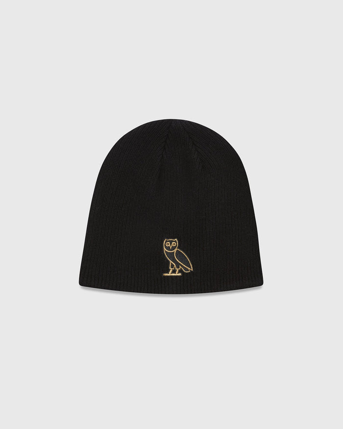 Black ribbed beanie with small gold owl embroidered on front.