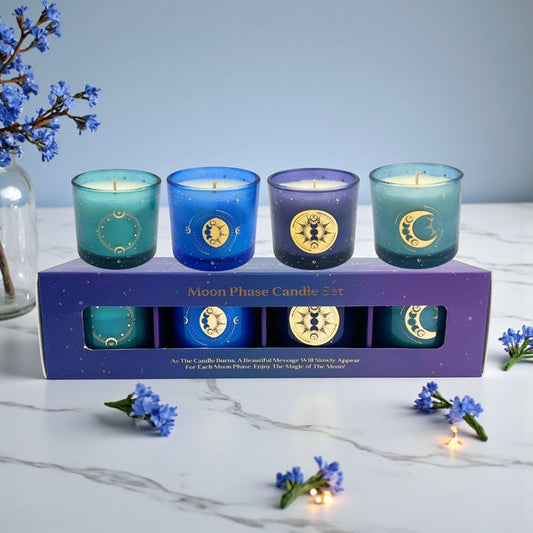 Set of four blue candles with celestial designs in front of their packaging box on a light surface.