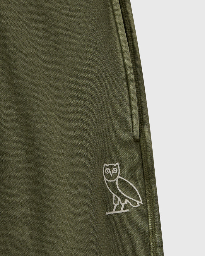Cypress green sweatpant with ribbed texture and small white owl embroidery on leg.