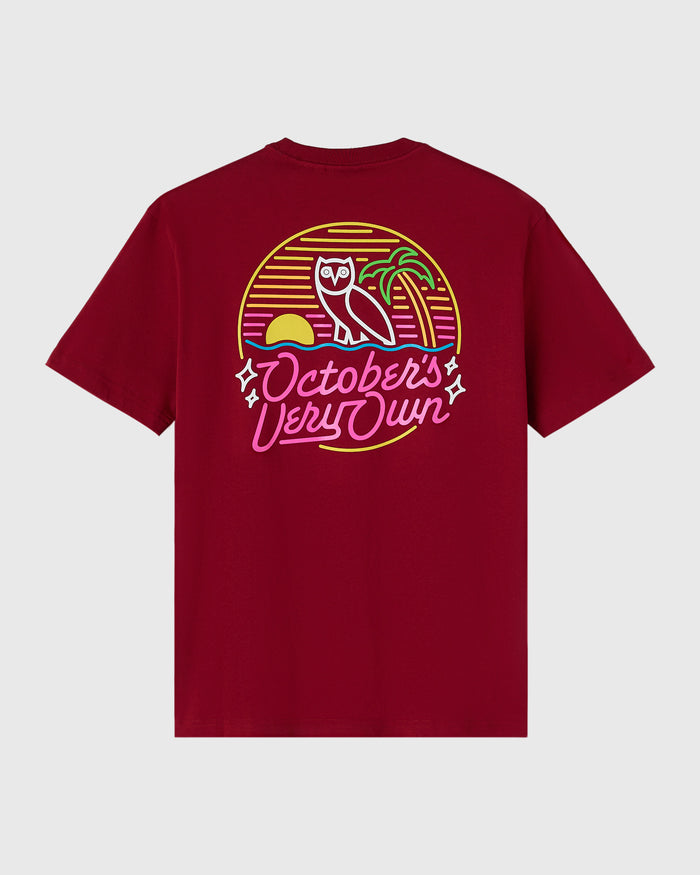 Deep red t-shirt with neon-style graphic featuring an owl, palm tree, sun, and "October's Very Own" text in yellow, pink, and