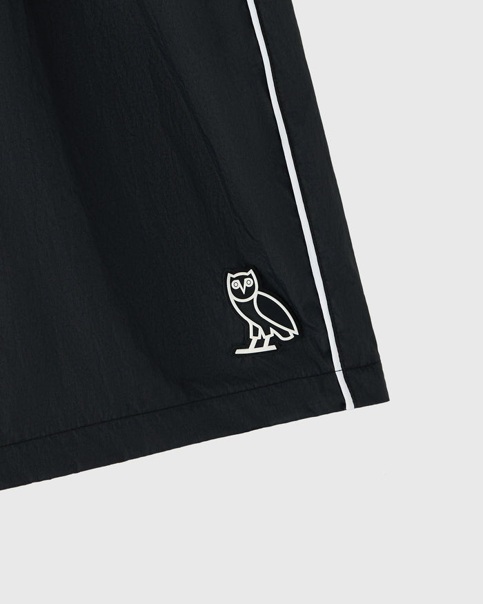 Black nylon track short with white side stripe and owl embroidered logo on thigh.