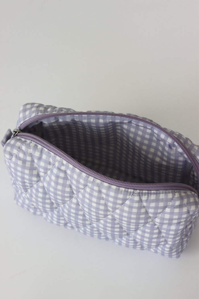 A quilted cosmetic pouch with a lavender and white gingham pattern, shown open to reveal a matching lavender interior lining.