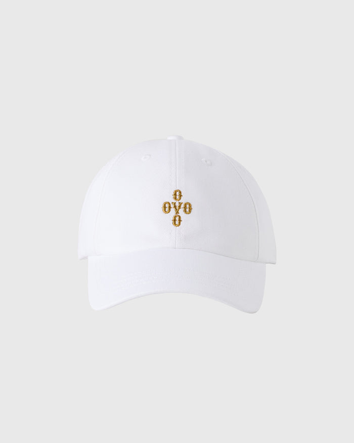 White baseball cap with gold embroidered cross design and pom pom on crown.