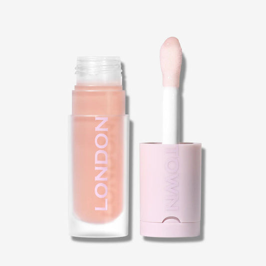 A tube of Quench Glow Buttery Lip Oil - Au Naturale by LONDONTOWN, with its applicator wand beside it on a plain light background, delivers plush shine and deep hydration for irresistibly glossy lips.