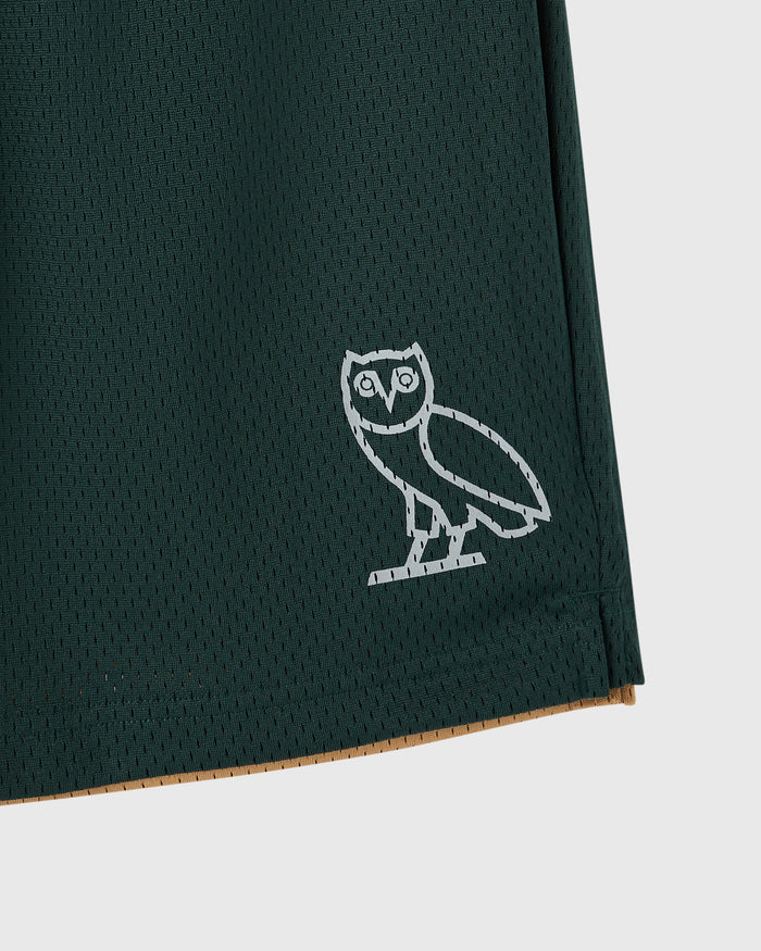 Dark green mesh short with white owl embroidery on thigh and camel-colored reverse side visible at hem.