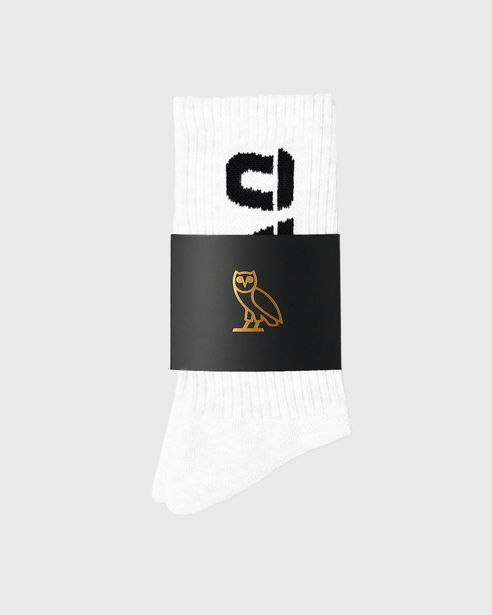 White ribbed crew socks with black text and gold owl logo on black band.