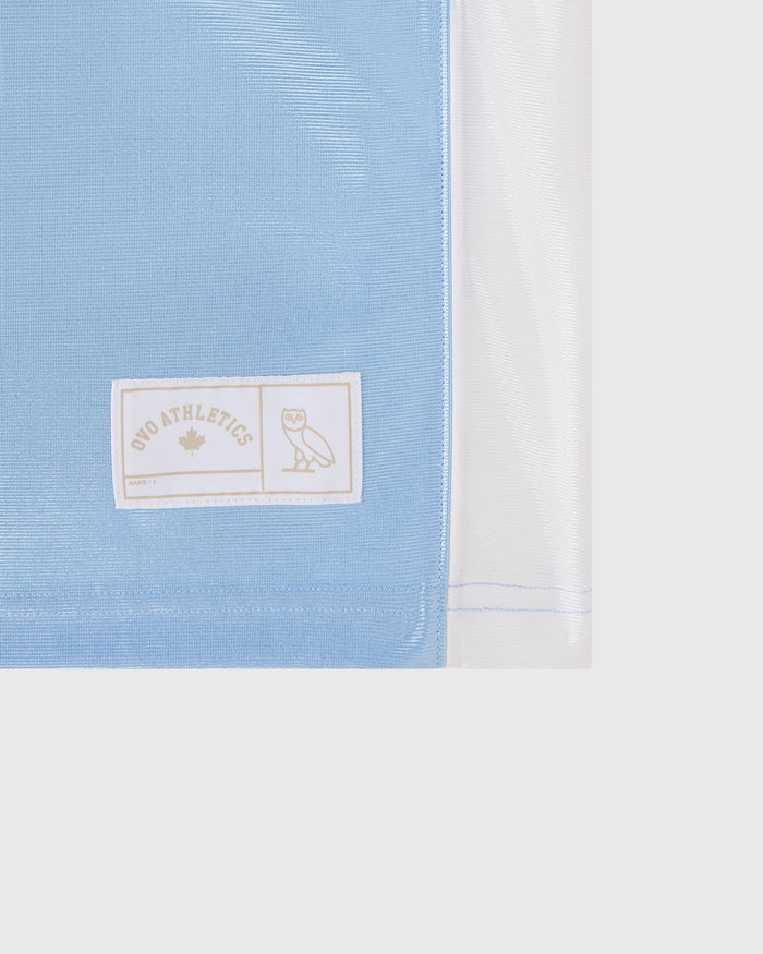 Light blue and white t-shirt with "OVO Athletics" label and owl logo on chest.