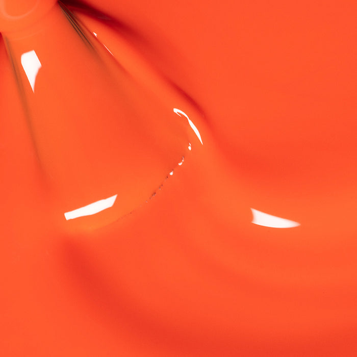 Close-up of Manucurist's Sunset nail polish—a glossy, vibrant orange shade with a smooth, shiny finish and light reflections, forming a flowing, abstract pattern.