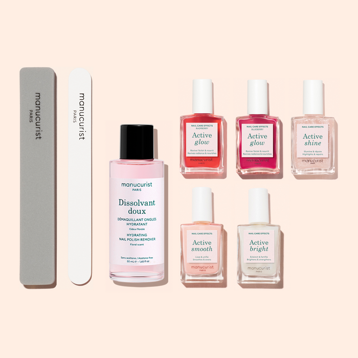 The Manucurist Super Active Manicure Kit features seven essential products—ideal for nail prep and care—including a gray nail file, a white buffer, a pink nail polish remover bottle, and five treatment bottles in shades of pink, red, and clear—all beautifully arranged on a light background to provide everything you need for a flawless manicure.