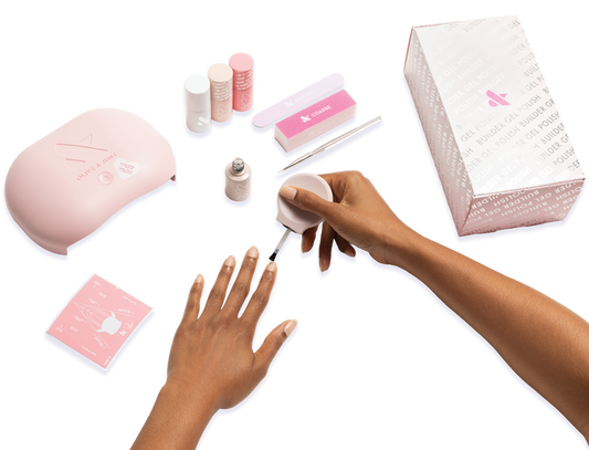The Gel Mani System + Builder Gel Kit - 6 showing a hand applying gel polish with lamp, nail care tools, and packaging visible