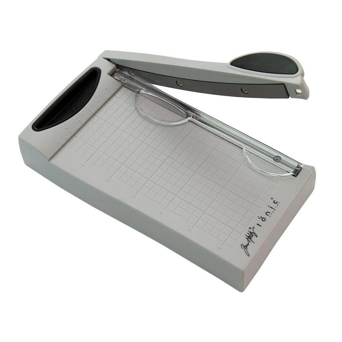 Tim Holtz - Guillotine Mini Trimmer 6.25". The Tim Holtz 6.25 inch / 16cm Mini Trimmer has many features not found in similar products. This product is portable and lightweight. It is perfect for trimming photographs and creating card fronts. Available at Embellish Away located in Bowmanville Ontario Canada.