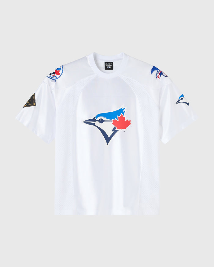 A white Toronto Blue Jays athletic t-shirt with a large blue jay and red maple leaf logo on the front, featuring team logos on the shoulders and sleeves, displayed against a light gray background.