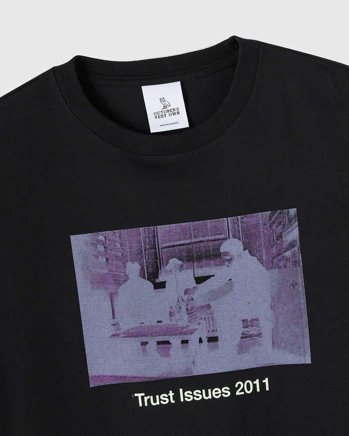Black crewneck t-shirt with purple-tinted surveillance camera image and "Trust Issues 2011" text printed on chest.
