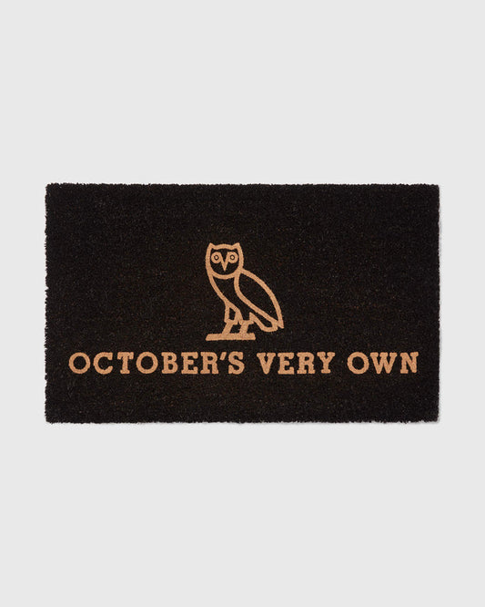 Black doormat with tan owl illustration and "October's Very Own" text.