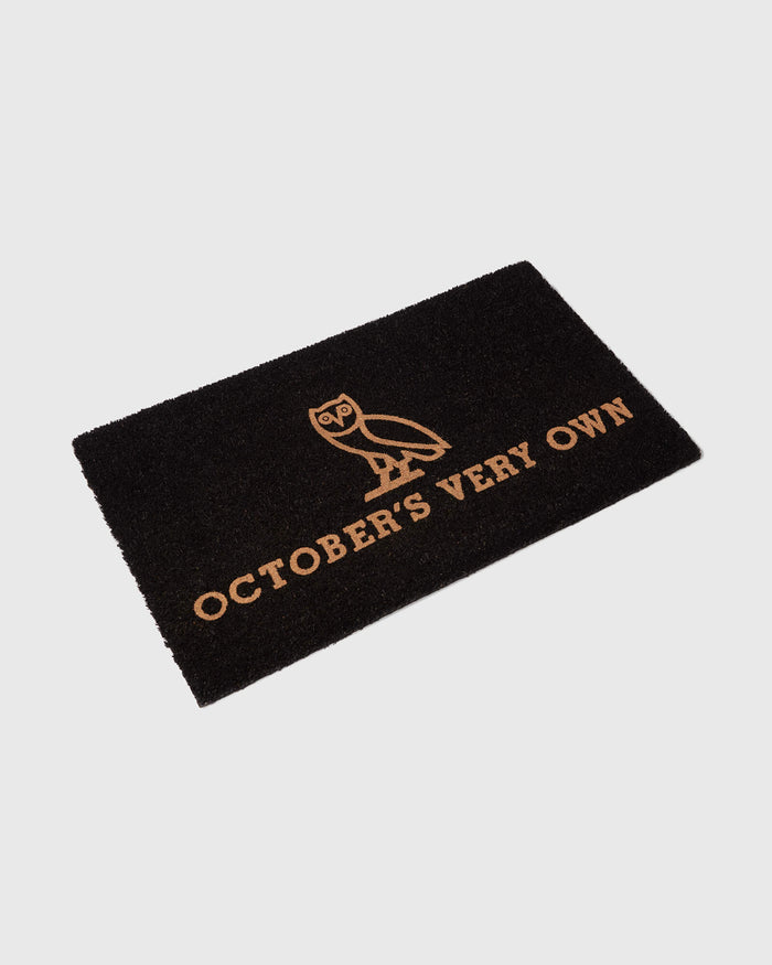 Black welcome mat with tan owl design and "Octobers Very Own" text.