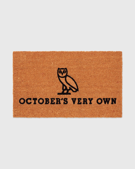 Brown coir welcome mat with black owl illustration and "October's Very Own" text.